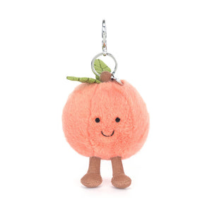 Jellycat peach plush keychain with a smiling face and brown feet on a white background.