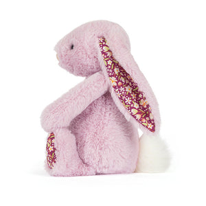 Side view of a Jellycat lilac plush bunny with floral patterned ear lining and a white fluffy tail on a white background. 