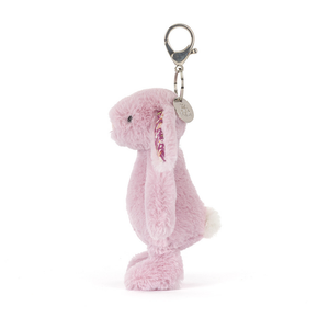 Side view of a Jellycat lilac bunny keychain with a fluffy white tail and floral ear lining. The bunny is on a white background. 