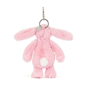 Back view of a Jellycat pink plush bunny keychain with a white fluffy tail on a white background.