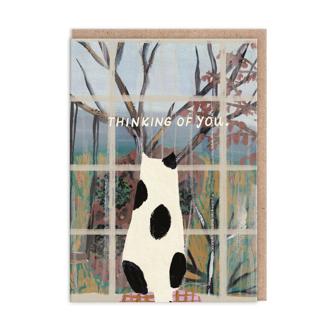 Greeting card with an illustraton of a black and white spotty cat looking out the window at trees and text saying "Thinking of You".