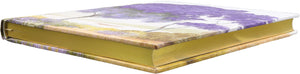 Hardback notepad with gilded gold page edges lying flat on a white background. 