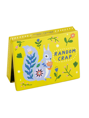 Front view of a yellow pocket box with the text 'RANDOM CRAP' on the cover, featuring illustrations of a grey squirrel holding an acorn, flowers, and leaves.