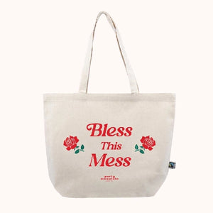 tote bag with centred red text that reads "bless this mess". two red roses frame the word "this"