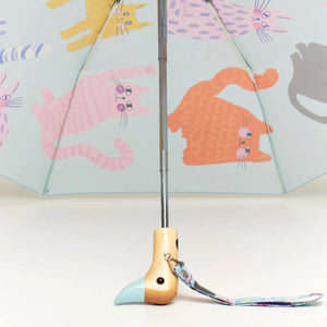 Inside view of an opened blue umbrella with an abstract cat print and a wooden duck head shaped handle on a white background. 