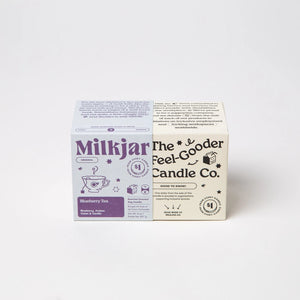 Purple box cover with Milkjar branding beside white box with the text 'the feel-gooder candle co.' on a white background. 