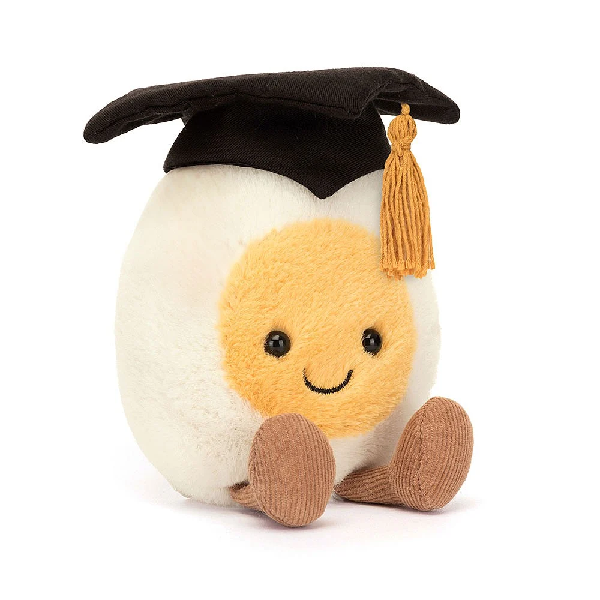adorably soft plushie of a smiling boiled egg with feet and a graduation hat by popular brand Jellycat.
