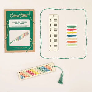 Wooden bookmark beside colourful threads and packaging on a light background.