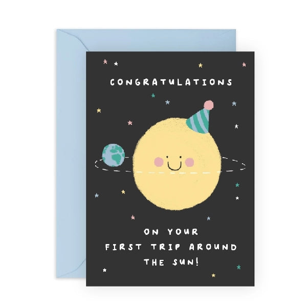 cute black birthday card with a smiling sun wearing a birthday hat. the earth spins around it. top text reads "congratulations" and bottom text reads "on your first trip around the sun!"