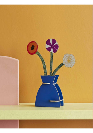 3D pop-up model in the shape of a blue vase containing three colorful flowers. The vase sits on a yellow base against a yellow wall.
