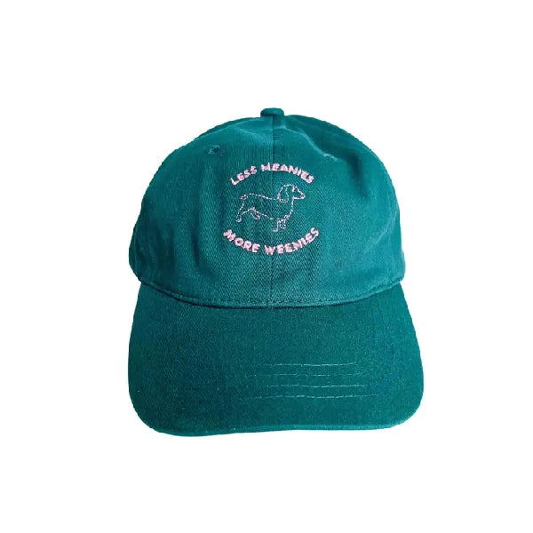 turquoise dad hat with a pink embroidered design. a sausage dog is surrounded by the text that reads "less meanies more weenies"