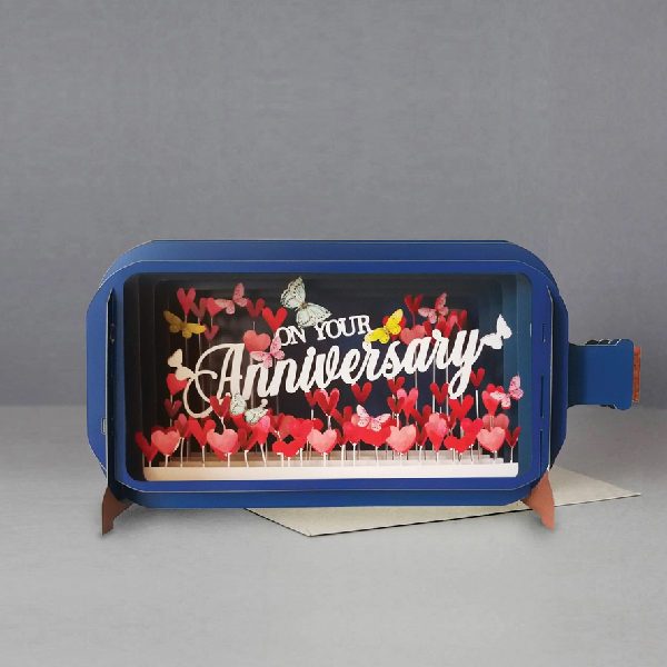 blue bottle pop up card. the intricate paper cuttings depict a planted hearts, butterflies, and a white text that reads "on your anniversary"