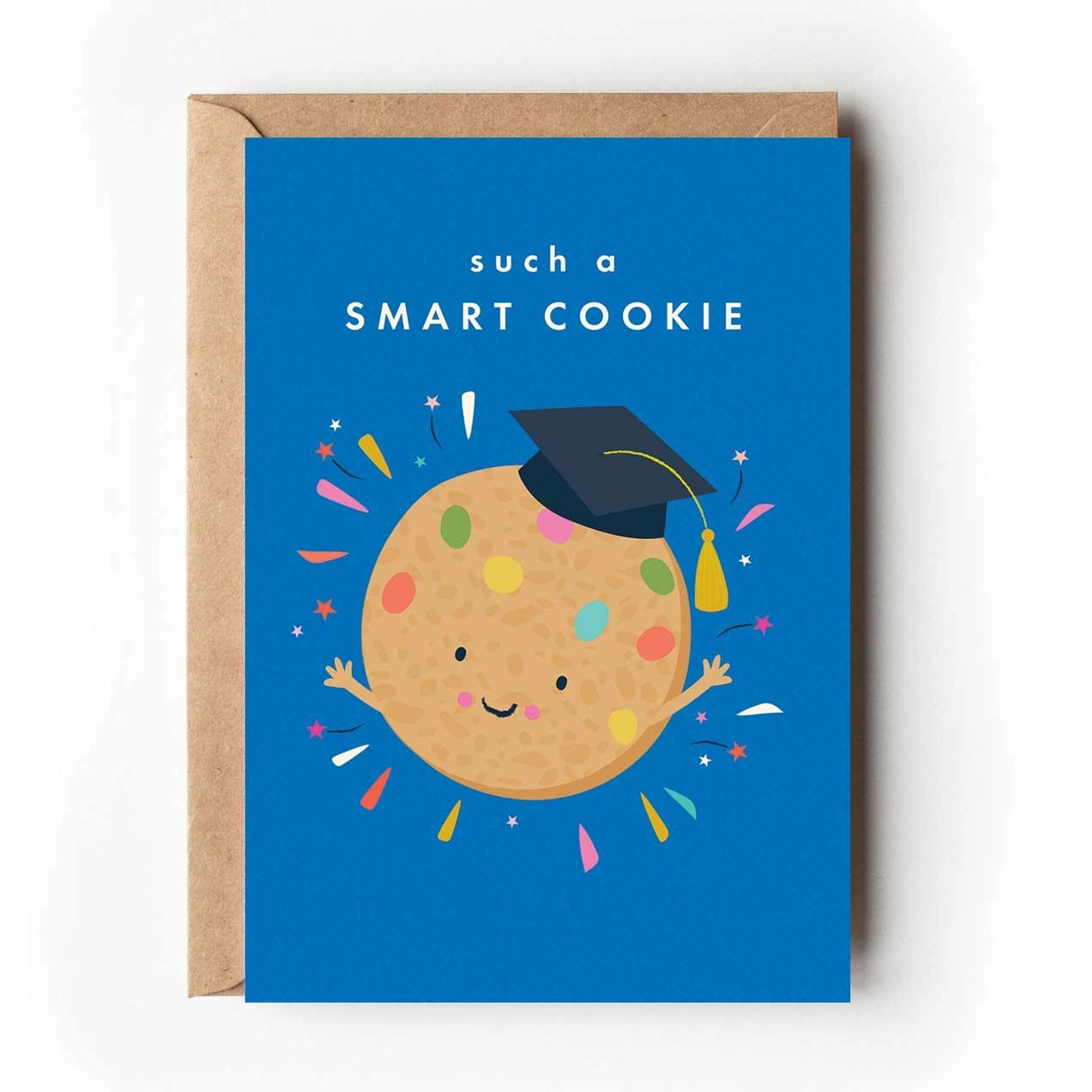 Greeting card featuring an illustration of a smiling cookie with colourful polka dots wearing a graduation hat as it waves it's arms in the air. Colourful stars and lines surround the cookie on a vibrant blue background with the text 'such a smart cookie'.