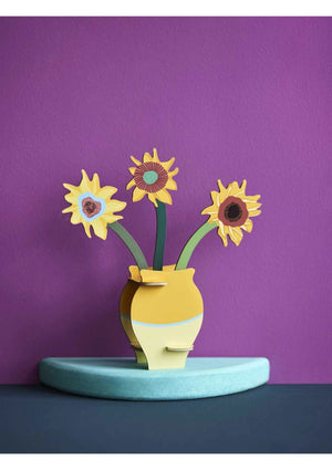 3D pop-up yellow vase model containing three sunflowers on a purple background.
