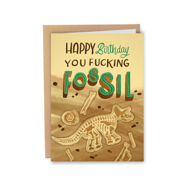 Greeting card with an illustration of dinosaur fossils on a brown background with the text 'Happy Birthday you fucking fossil'. 