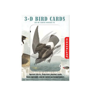 white and blue-grey packaging box. top text reads "3-d bird cards, jeu de cartes oiseaux fx". box has an open window showing the back of one of the cards. a black bird is diving towards water. a lighter version of the illustration is duplicated on the card, giving the impression of the 3D effect. kikkerland product on white background